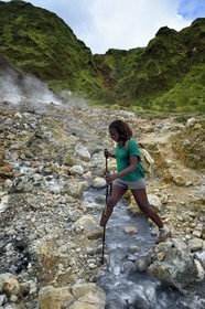 Caribbean, Dominica Island, Castle Bruce, Morne Trois Pitons National Park listed as World heritage by UNESCO, Valley of Desolation, hiker crossing a river of hot springs, whose unique color is due to the presence of calcium, carbon, sulfur and iron, on the trail leading to Boiling Lake