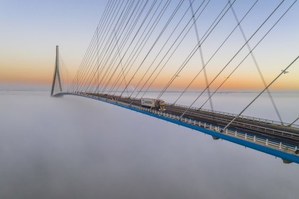 France, between  Calvados and Seine Maritime, the Pont de Normandie (Normandy Bridge) emerges from the morning mist of autumn and spans the Seine to connect the towns of Honfleur and Le Havre
