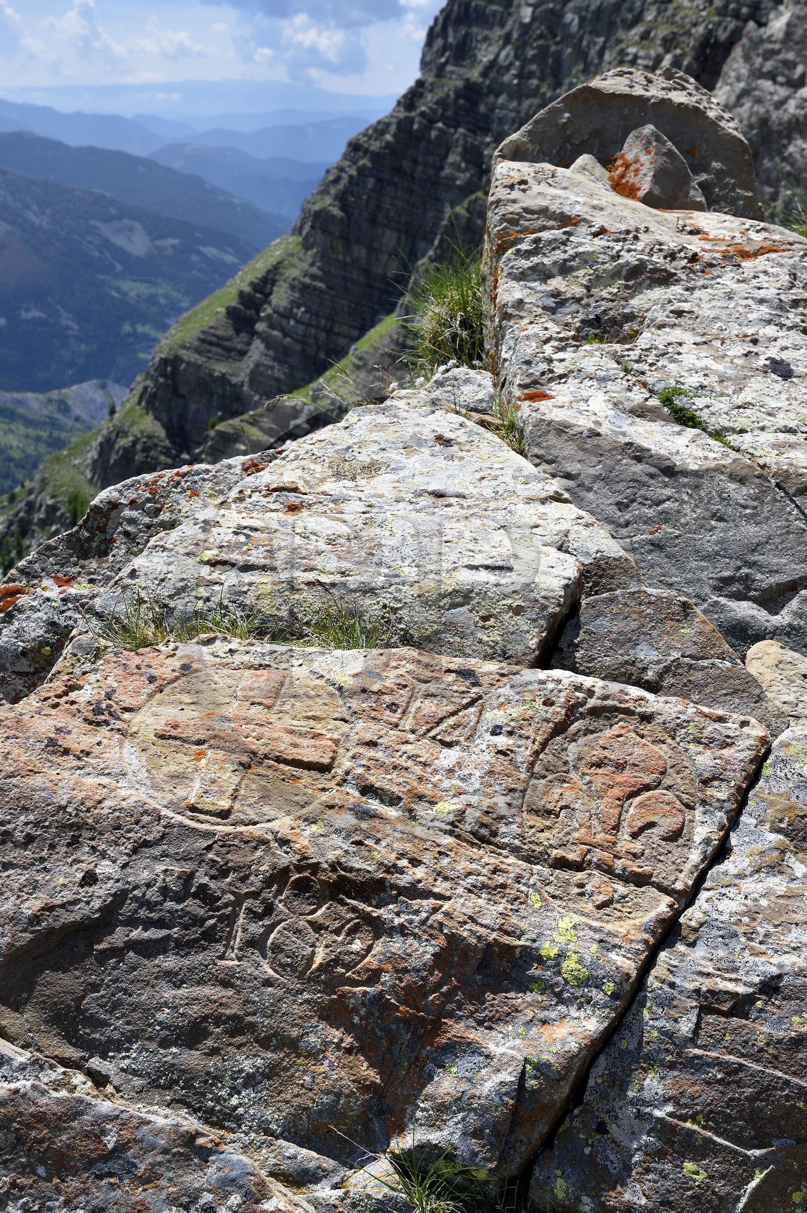 France, Alpes de Haute Provence, Uvernet Fours, Mercantour National Park, Ubaye valley, lake tour hiking trail of the Cayolle pass at the Pas du Lausson, boundary engraved on rocks delimiting the border between the Duchy of Savoy and the County of Nice, Haut-Var Valley and Lake Lausson (Alpes-Maritimes) in the background