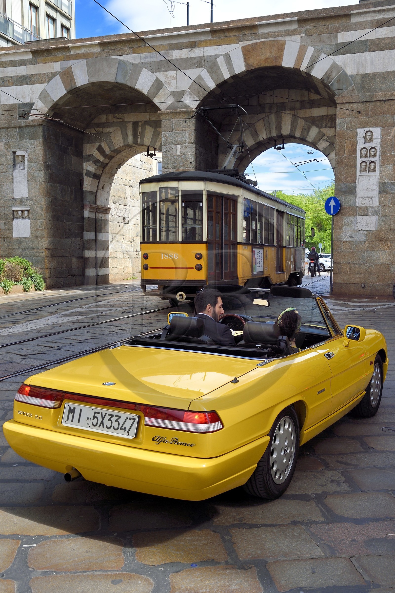 Italie, Lombardie, Milan, cabriolet Alfa Romeo Duetto Spider jaune devant la Porta Nuova qui est faisait partie de l'enceinte médiévale