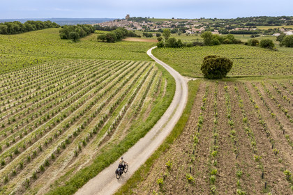 France, Vaucluse, Chateauneuf du Pape, cycling on the Coste Froide path on the Crau plateau and the Chateauneuf du Pape dungeon in the background (aerial view)