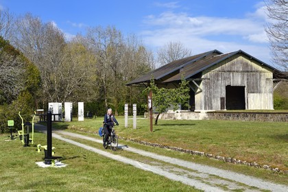France, Dordogne, Périgord Vert, Saint Jean de Cole labelled Les Plus Beaux Villages de France (The Most Beautiful Villages of France), cyclist on the green lane of the Flow Vélo cycle route which follows the old railway line, hangars of the old station