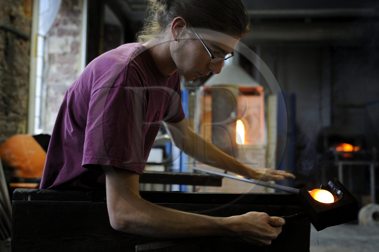 France, Moselle (57), Meisenthal, Thibaut souffleur au Centre international d’Art verrier (CIAV) s’aide d’une mailloche en bois pour arrondir le verre et faire une boule de Noël en verre régulière