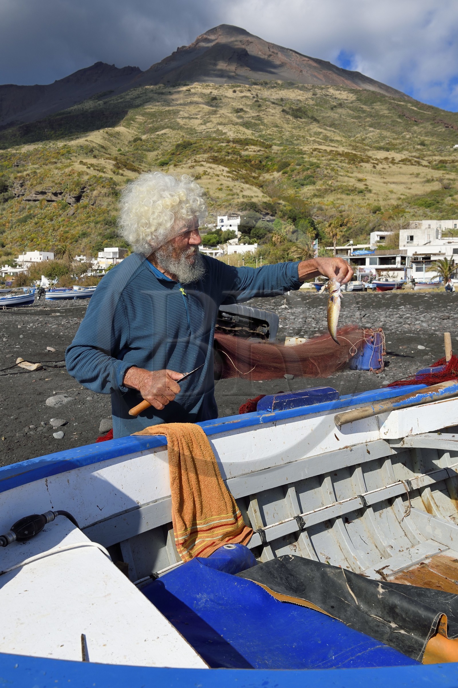 Italie, Sicile, iles Eoliennes, classées Patrimoine Mondial de l'UNESCO, ile de Stromboli, le pecheur Roberto Cusolito vidant ses poissons sur la plage de Scari et le volcan du Stromboli en arrière plan