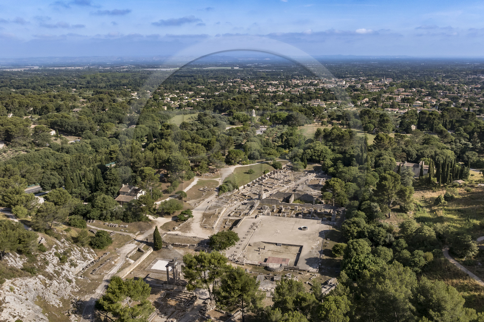France, Bouches du Rhone, Regional Natural Park of the Alpilles, Saint Remy de Provence, site archéologique de Glanum and the city in the background (aerial view)