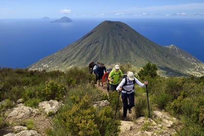 Italie, Sicile, iles Eoliennes, classées Patrimoine Mondial de l'UNESCO, Ile de Salina, randonneurs au sommet de l'ancien volcan Monte Fossa delle Felci avec le volcan jumeau Monte dei Porri, les Iles de Filicudi et d'Alicudi en arrière plan
