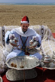 Morocco, Oriental Region, man in ceremonial cloth serving mint tea on the beach