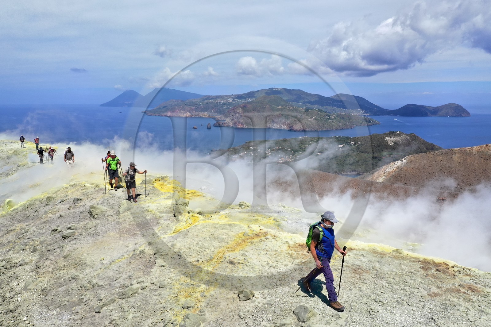 Italie, Sicile, iles Eoliennes, classées Patrimoine Mondial de l'UNESCO, ile de Vulcano, randonneurs en bordure du cratère du volcan della Fossa marchant à travers les fumerolles soufrées, l'Ile de Lipari puis Ile de Salina en arrière plan (vue aérienne)