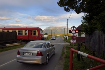 Roumanie, Transylvanie, Zarnesti, train au passage à niveau et les monts Fagaras dans les Carpates du Sud