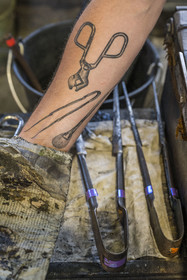 France, Moselle, Meisenthal, Centre international d'Art verrier (CIAV) (international glass centre), the blowing workshop, tattoos on the arm of the glassmaker Geoffrey Richard