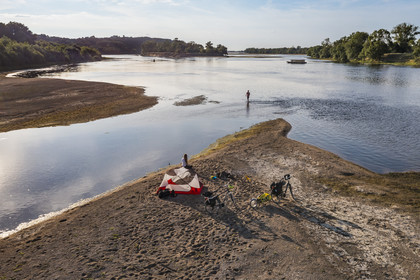 France, Maine-et-Loire, Loire valley listed as World Heritage by UNESCO, cycling along the banks of the Loire, camping for the night on one of the sandbanks forming islands on the Loire, a gabarre (traditional flat-bottomed boat) in the background (aerial view)