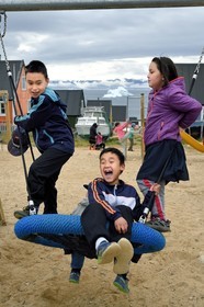 Groenland, cote Nord-Ouest, mer de Baffin, Qaanaaq ou Nouvelle Thule, des enfants inuit jouent sur une aire de jeux pendant la récréation, un iceberg en arrière plan