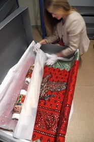 France, Alpes-de-Haute-Provence (04), vallée de l'Ubaye, Barcelonnette, villa mexicaine connue sous le nom de Villa Sapinière, Musée de la vallée, la conservatrice Hélène Homps dans la réserve du musée observe une robe brodée China poblana, costume national mexicain porté par les épouses des barcelonnettes pour le 14 juillet au Mexique