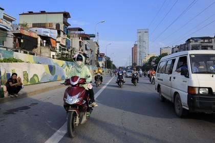 Vietnam, Hanoï, circulation en moto sur Tran Quang Khai le long de la digue dont la fresque a été réalisée pour le Millénaire de Hanoï, la conductrice est emmitouflée contre le soleil par 35° et protégée contre la pollution