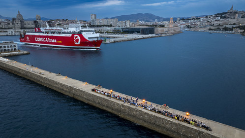 France, Bouches-du-Rhône (13), Marseille, Zone Euroméditerranée, grand port maritime de Marseille (GPMM), la digue du large, convives attablés à une grand table de banquet dressée par le chef Emmanuel Perrodin dans le cadre des Diners Insolites, un ferry de Corsica Linea quitte le port, le Mucem, le Fort Saint-Jean et la basilique Notre Dame de la Garde en arrière plan (vue aérienne)