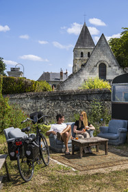 France, Maine-et-Loire, Loire valley listed as World Heritage by UNESCO, Gennes-Val-de-Loire, cycling on the banks of the Loire, stop at the bookstore-café L'Idiot of the association Gabare And Co in the former school of the Girls of Chênehutte, the church of notre dame des tuffeaux in the background