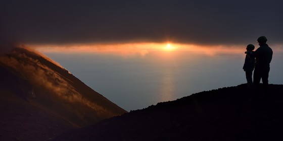 Italie, Sicile, iles Eoliennes, classées Patrimoine Mondial de l'UNESCO, ile de Stromboli, randonneurs observant les fumerolles d'une éruption sur les pentes du volcan actif au coucher de soleil