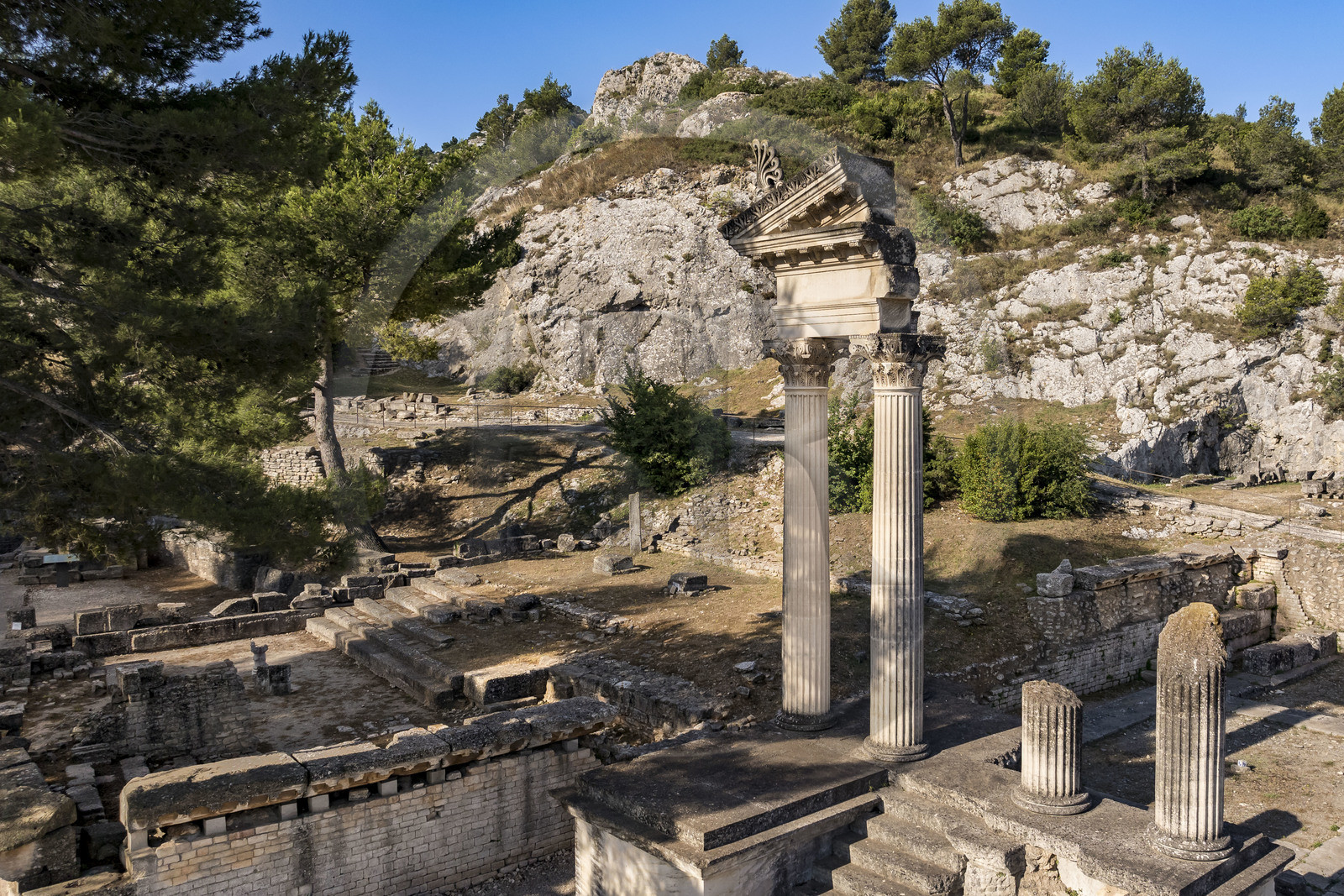 France, Bouches-du-Rhône (13), Parc Naturel Régional des Alpilles, Saint-Rémy-de-Provence, site archéologique de Glanum, colonnes et entablement reconstitués du petit temple géminé du premier forum au premier plan à droite