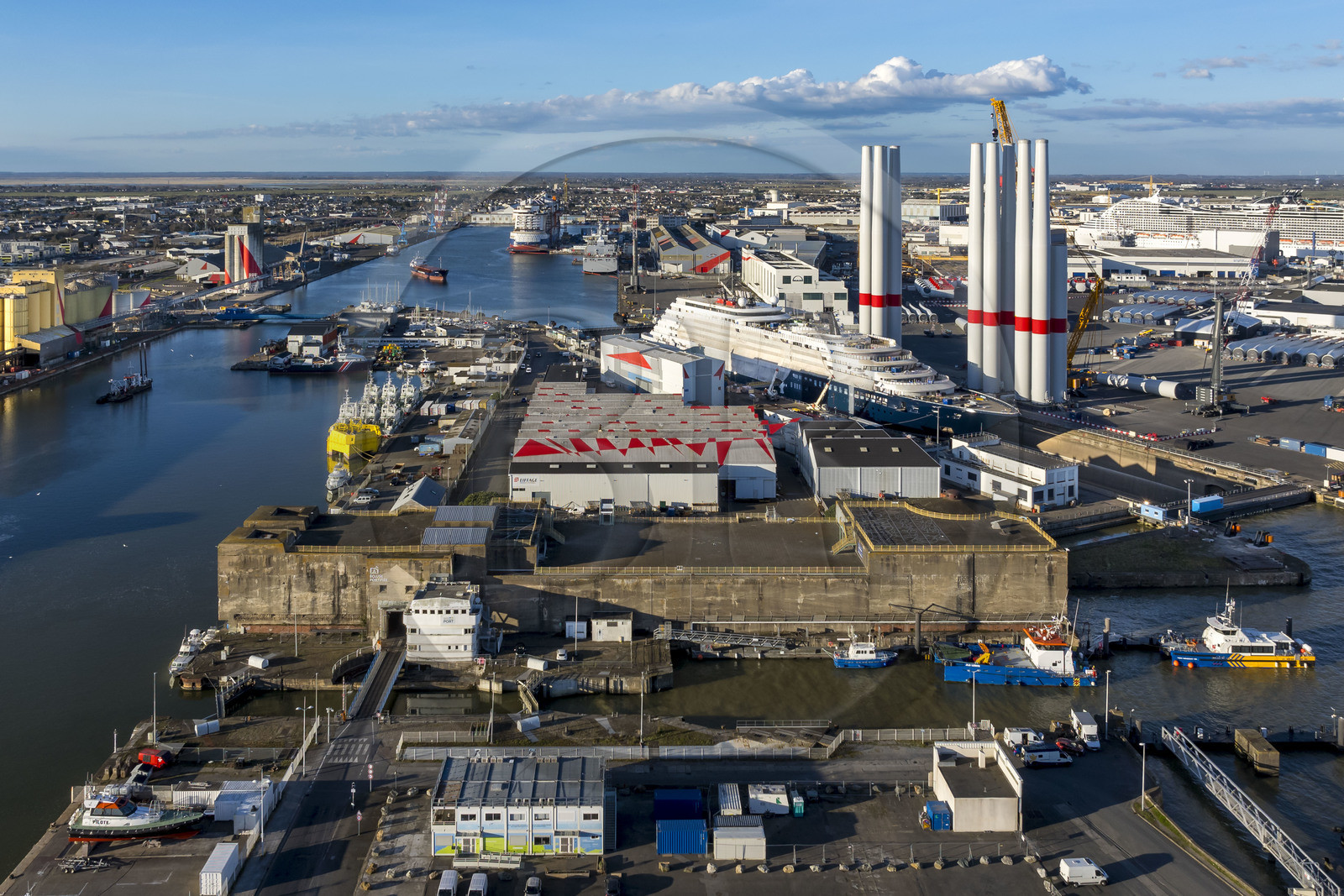 France, Loire-Atlantique (44), Saint-Nazaire, l’écluse Est et l'écluse fortifiée de l'ancienne base sous-marine allemande construite lors de la dernière guerre mondiale au premier plan et le chantier du super-yacht de luxe Ritz-Carlton Luminara dans la forme Joubert, les tours d'éoliennes à droite sont stockées avant embarquement, le paquebot de 333m MSC World America construit par les Chantiers de l'Atlantique en arrière plan (vue aérienne) France, Loire-Atlantique (44), Saint-Nazaire, l’écluse Est et l'écluse fortifiée de l'ancienne base sous-marine allemande construite lors de la dernière guerre mondiale au premier plan et le chantier du super-yacht de luxe Ritz-Carlton Luminara dans la forme Joubert, les tours d'éoliennes à droite sont stockées avant embarquement, le paquebot de 333m MSC World America construit par les Chantiers de l'Atlantique en arrière plan (vue aérienne)