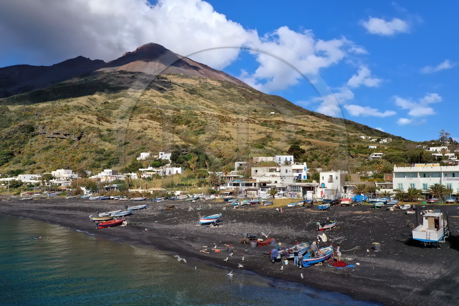 Italie, Sicile, iles Eoliennes, classées Patrimoine Mondial de l'UNESCO, ile de Stromboli, pecheurs sur la plage de Scari et le volcan actif du Stromboli en arrière plan (vue aérienne)