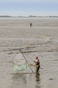 France, Charente-Maritime (17), Port-des-Barques, pêcheur au carrelet et cycliste empruntant le tombolo de la Passe aux Boeufs qui relie le continent à l'Ile Madame à marée montante en arrière plan