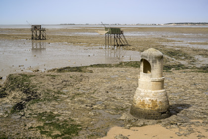 France, Charente Maritime, Port des Barques, Ile Madame, the Insurgent Well built by Communards deported in 1871 and huts on stilts called carrelets at low tide in the background