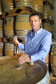 France, Ile de la Reunion, Saint Pierre, domaine de la distillerie Isautier, vieillissement des rhums vieux dans les chais entre 6 et 14 mois en futs neufs puis plusieurs années ensuite par lot en futs roux, Cyril Isautier directeur de la branche rhums et punchs du groupe Isautier fait un prélèvement à la pipette pour une dégustation