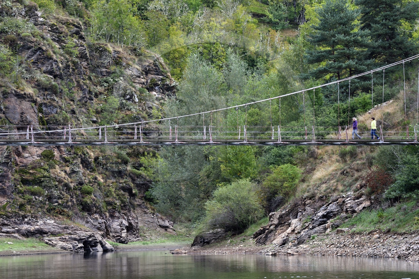 France, Cantal, Gorges de la Truyere (Truyere river canyon), Chaliers, two hikers cross the Valadour footbridge over the Truyere river