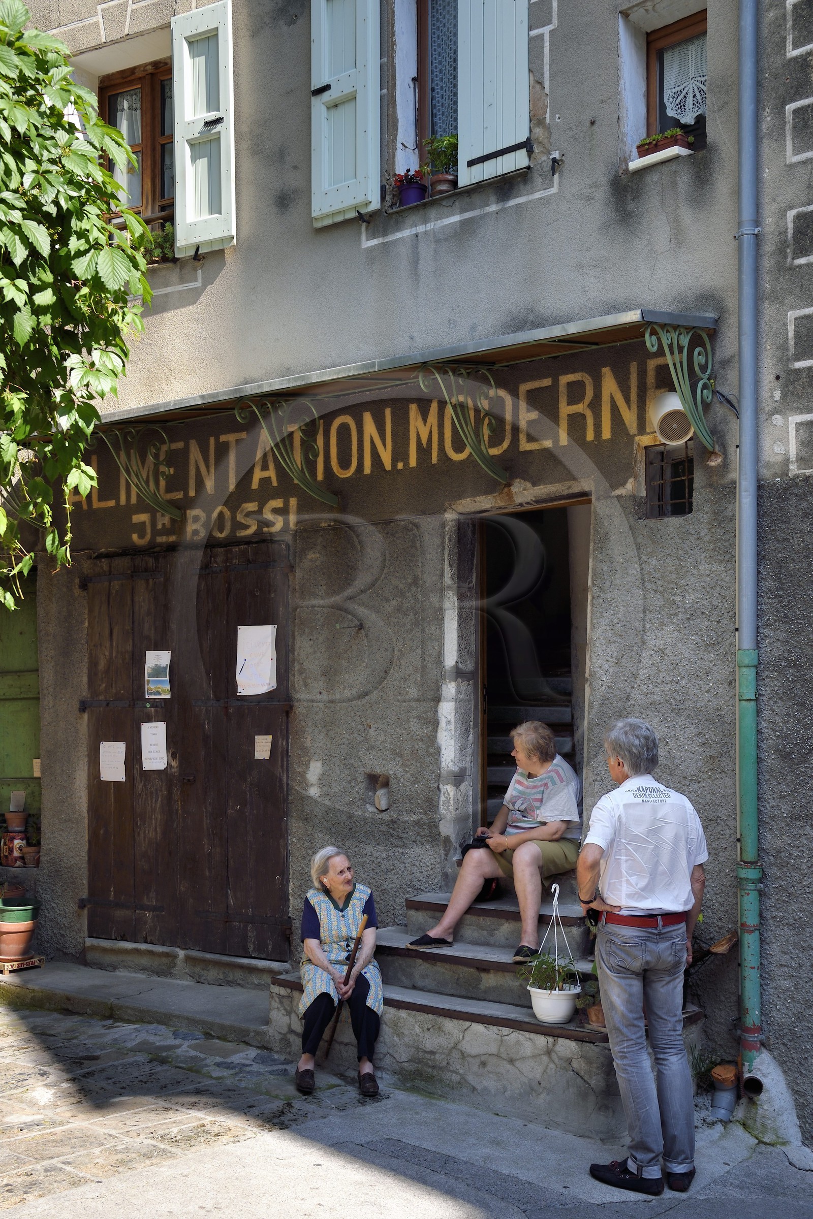 France, Alpes-de-Haute-Provence (04), cité médiévale d'Entrevaux fortifiée par Vauban, discussion devant l'épicerie de la vieille ville rue de la Porte Royale