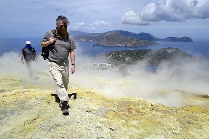 Italy, Sicily, Aeolian Islands, listed as World Heritage by UNESCO, Vulcano Island, hikers climbing the crater of volcano della Fossa through sulfur fumaroles, Lipari Island in the background