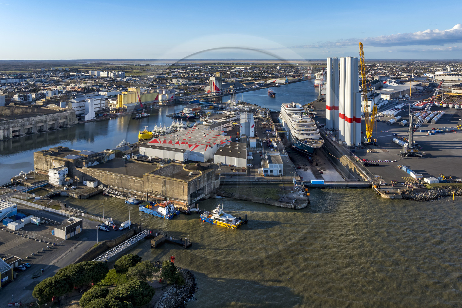 France, Loire-Atlantique (44), Saint-Nazaire, l’écluse Est et l'écluse fortifiée de l'ancienne base sous-marine allemande construite lors de la dernière guerre mondiale au premier plan et le chantier du super-yacht de luxe Ritz-Carlton Luminara dans la forme Joubert, les tours d'éoliennes à droite sont stockées avant embarquement (vue aérienne) France, Loire-Atlantique (44), Saint-Nazaire, l’écluse Est et l'écluse fortifiée de l'ancienne base sous-marine allemande construite lors de la dernière guerre mondiale au premier plan et le chantier du super-yacht de luxe Ritz-Carlton Luminara dans la forme Joubert, les tours d'éoliennes à droite sont stockées avant embarquement (vue aérienne)